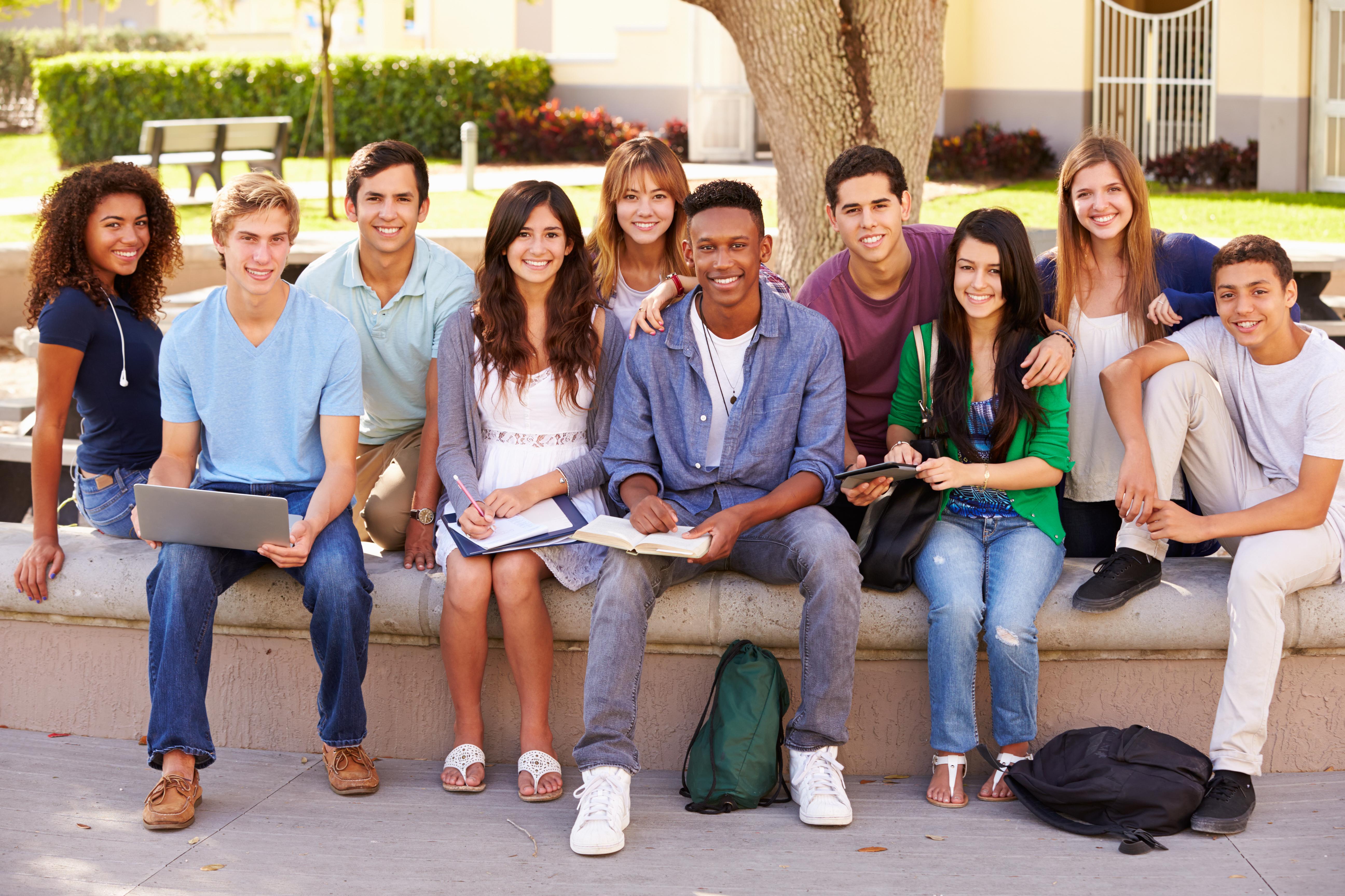 group of high school students sitting by a tree